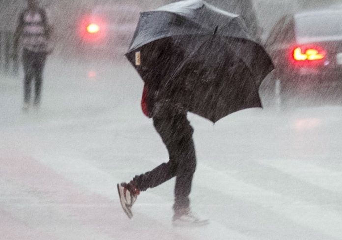 #Pracegover Na foto, uma pessoa segurando uma sombrinha e atravessando a rua sob forte chuva