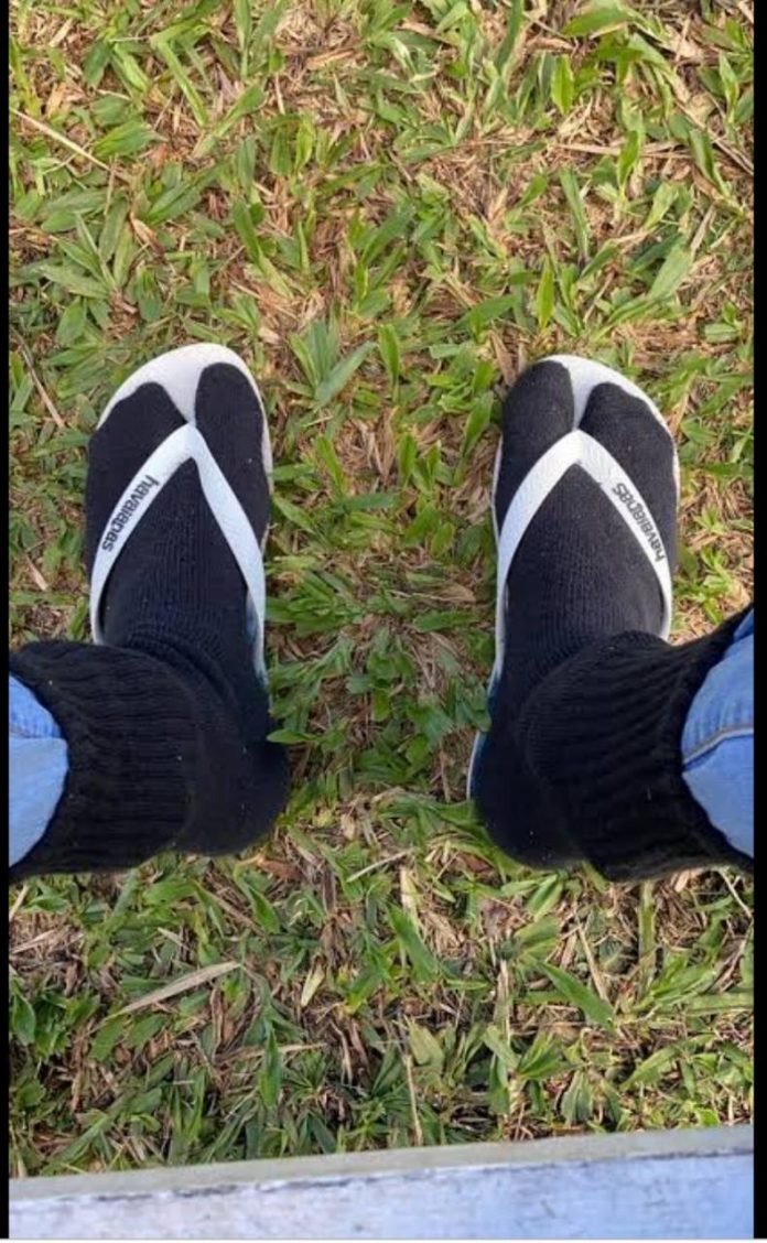 #Pracegover Foto: na imagem há chinelos, meias e gramado